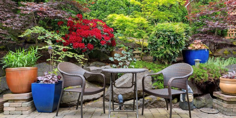 Garden backyard with lush plants landscaping and stone paver patio hardscape with patio furniture spring season Garden Design $ Planning in Wexford